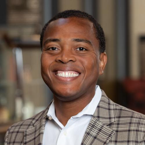 Antonio Burns wearing a checkered jacket and smiling.