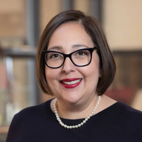 Patricia Gutierrez wearing pearls and glasses.