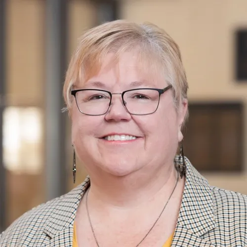 Janet Larsen wearing glasses and a necklace.