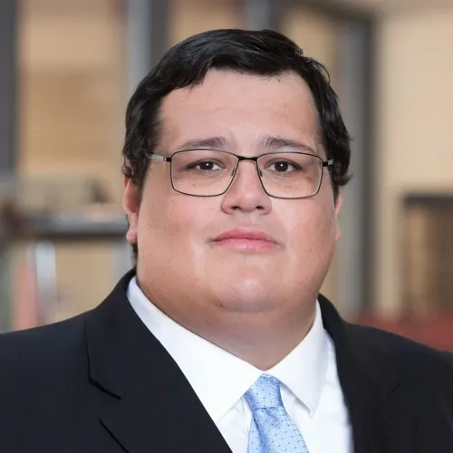Andres Temblador wearing a suit, tie and glasses.