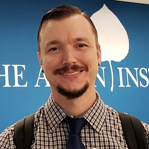 Daniel Sledge smiling and wearing a shirt and tie