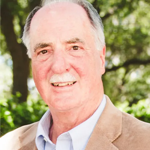 A man wearing a sport coat and collared shirt and smiling.