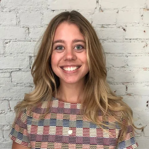 Erika Carlson smiling in front of a brick wall