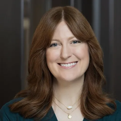 A woman wearing a necklace and smiling.
