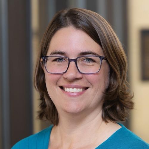 Esther Maier wearing glasses and smiling.