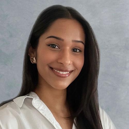 Nikhila Kalapatapu smiling in front of gray background
