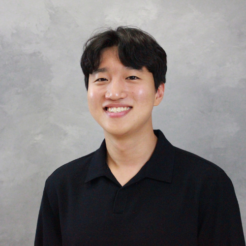 Taehyung Kim smiling in front of a gray background