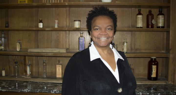 Dr. Carolyn Brown standing in front of shelves with pharmacy bottles