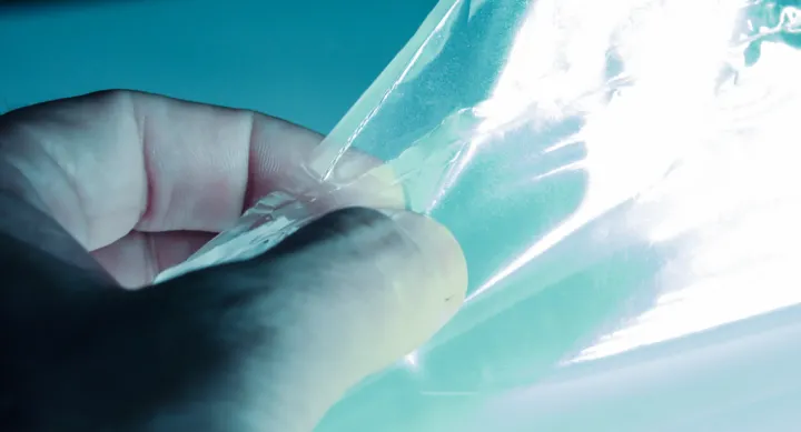 A hand touching a transparent sheet.
