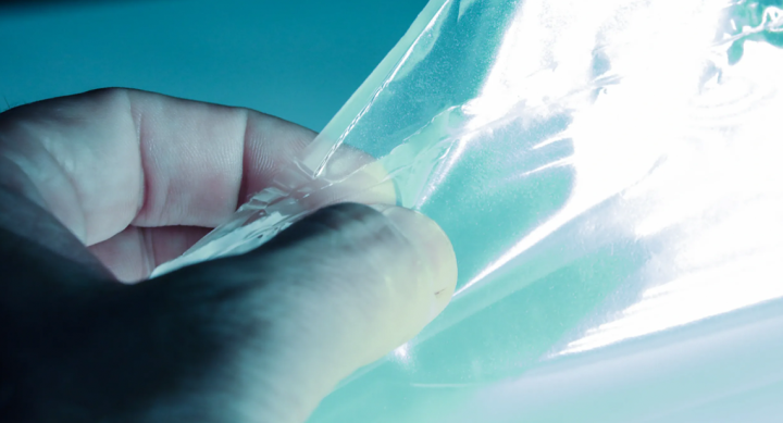 A hand touching a transparent sheet.