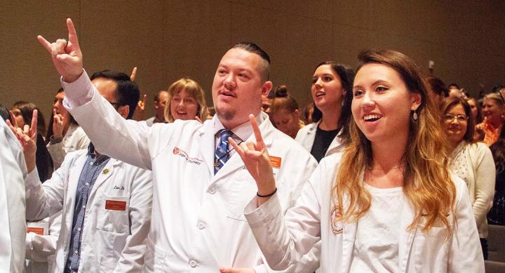 Two people giving the Hook 'em Horns hand gesture.