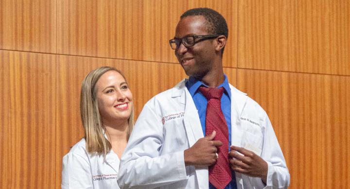 Pharmacy professor and pharmacy student in pharmacist's white coats.