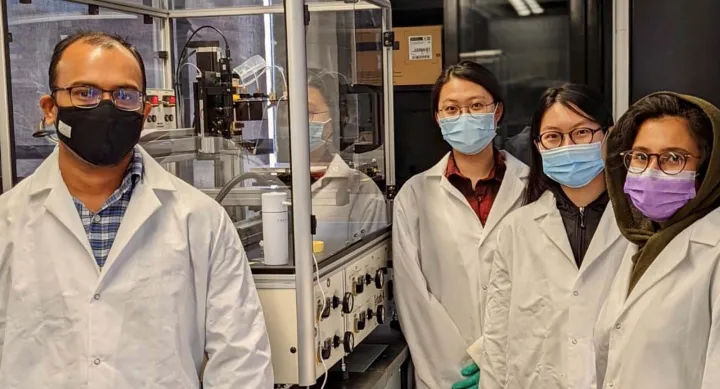 Four people members of PharmE3D lab wearing masks and lab coats.