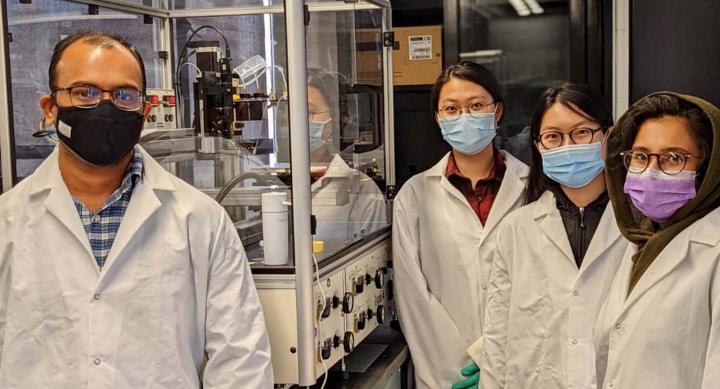 Four people members of PharmE3D lab wearing masks and lab coats.