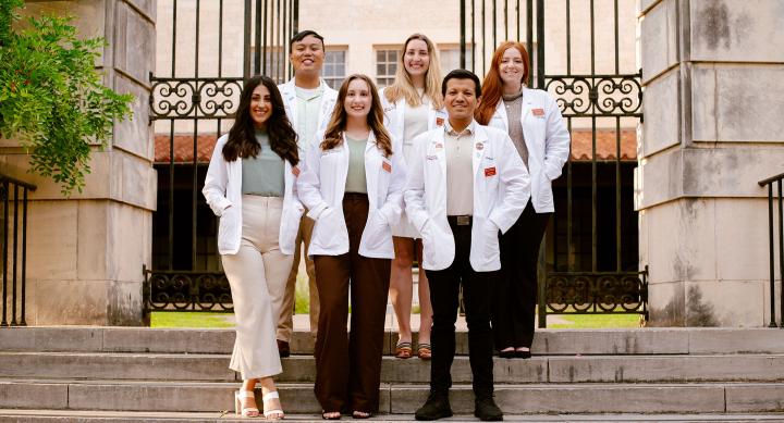 PharmD students on UT campus posed in group photo in front of gate to campus building
