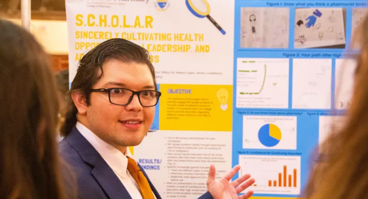 Texas Pharmacy student standing in front of his poster presentation board at the conference.