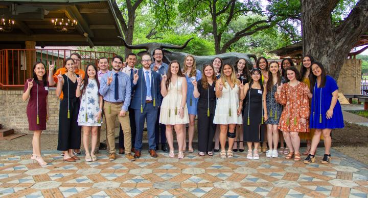 A group of people giving the Hook 'em Horns hand gesture.