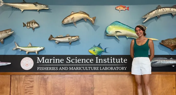 A woman standing in front of some mounted fish and a sign that says "Marine Science Institute."
