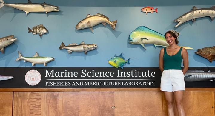 A woman standing in front of some mounted fish and a sign that says "Marine Science Institute."