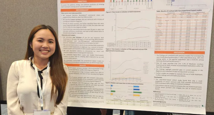A woman standing in front of a research poster and smiling.