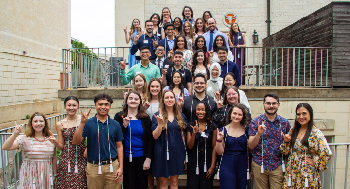 A group shot of Texas Pharmacy Honors Day students wearing their cords and holding up the Hook 'Em horns.