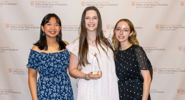 Three female members of the PPA Student Group pose together with a trophy.