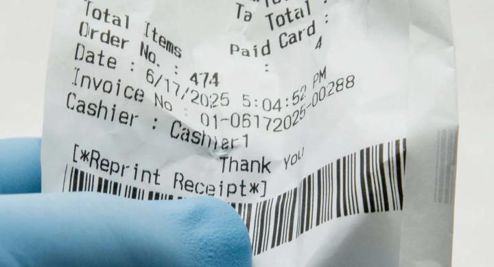 Someone wearing nitrile gloves and holding a store receipt.