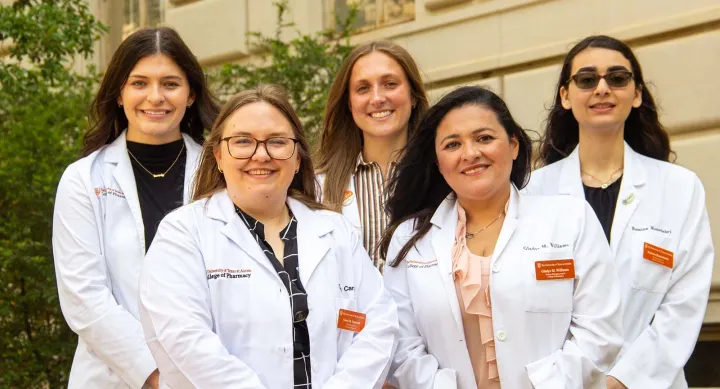 Five women wearing white coats and smiling.