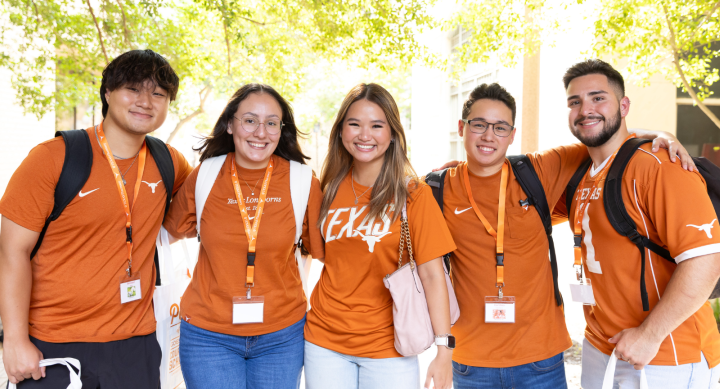 Five Texas Pharmacy students pose together, smiling brightly to camera wearing burnt orange t-shirts and lanyards.