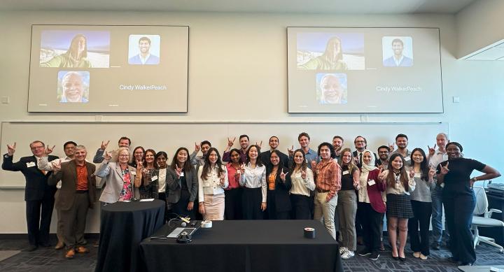 Nexxus Project group standing in conference room and giving hook 'em horns hand sign