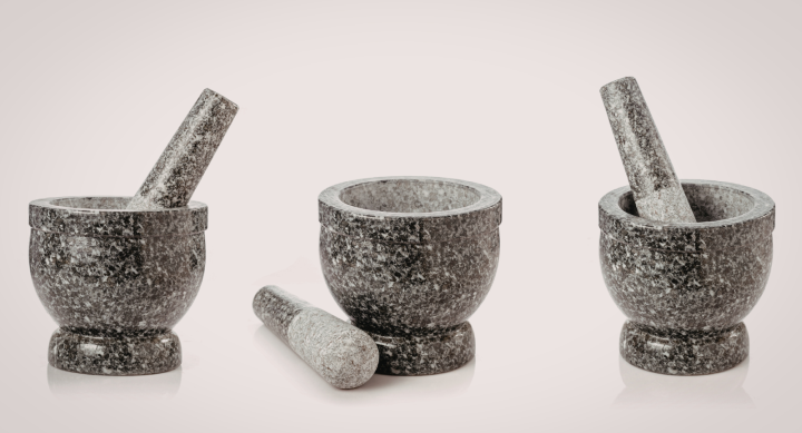 Three grey stone mortar and pestles on display against a cream background.