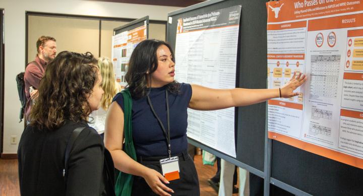 A woman gesturing at a research poster.