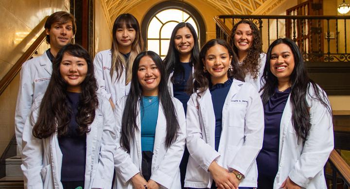 Eight students in white coats smiling.