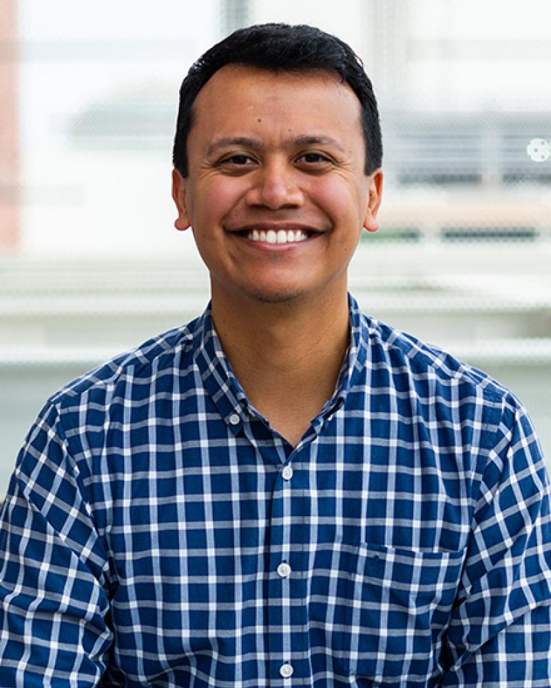 Dr. Isaac Perales smiling and wearing checkered shirt