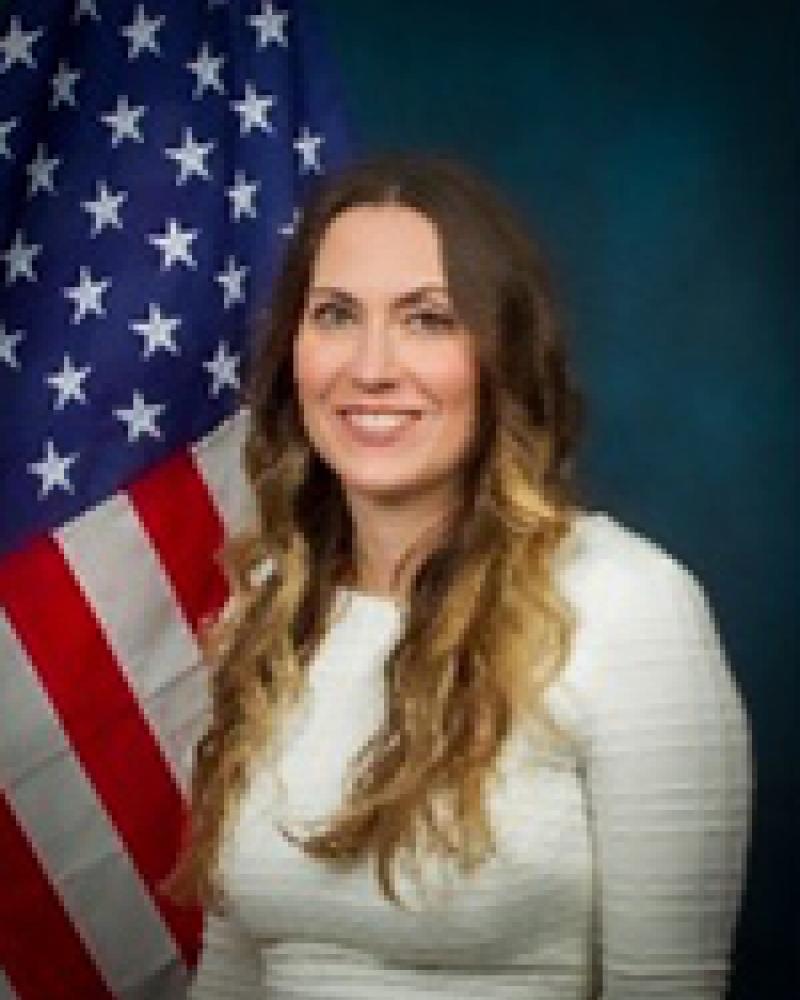 Kathleen Ready smiling in front of an American flag