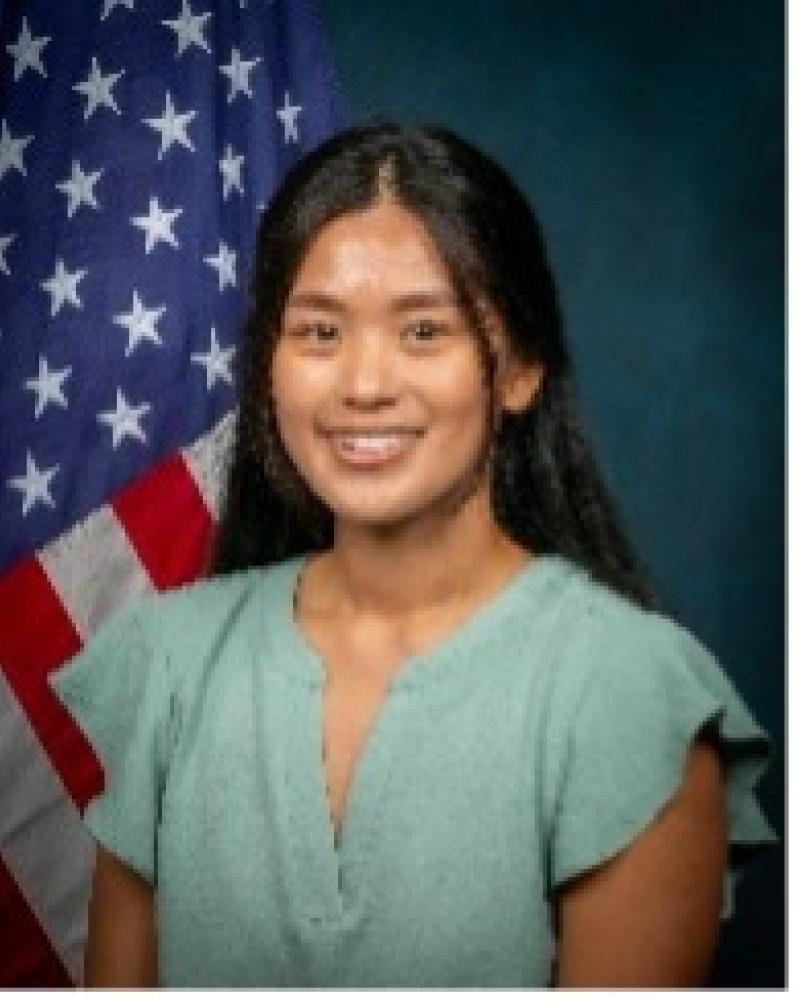Wendy Zheng smiling in front of an American Flag