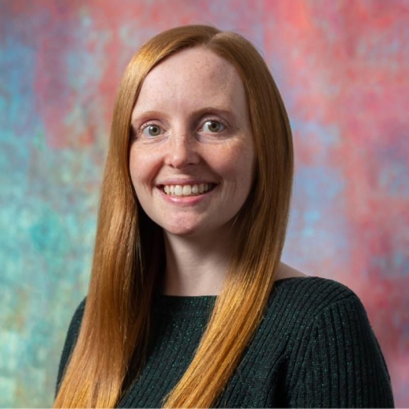 Louise Ince smiling in front of a multicolored background