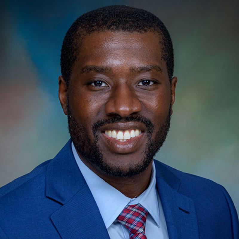 Dr. Emmanuel Enwere smiling and wearing a blue suit