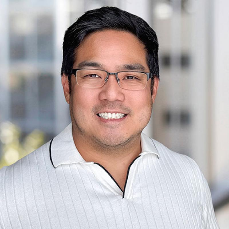 Dr. Eric Ho smiling in front of a window